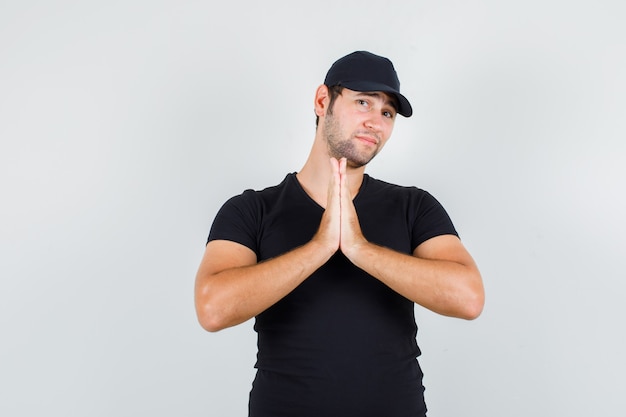 Entregador de mãos dadas em gesto de oração em camiseta preta