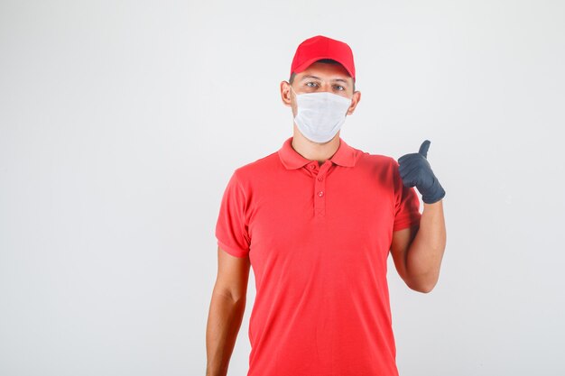 Entregador de uniforme vermelho, máscara médica, luvas mostrando algo com o dedo