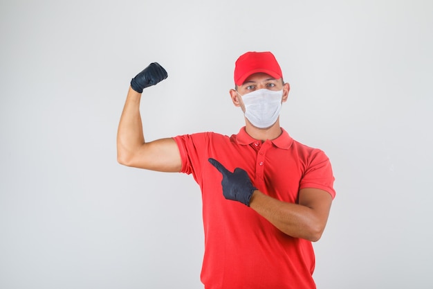 Entregador de uniforme vermelho, máscara médica, luvas mostrando os bíceps e parecendo poderoso