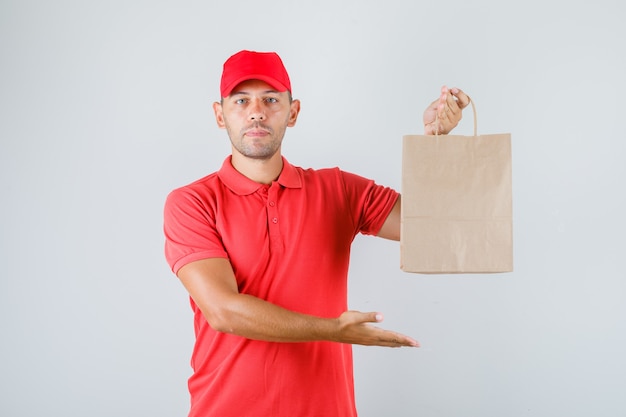 Entregador de uniforme vermelho segurando um saco de papel