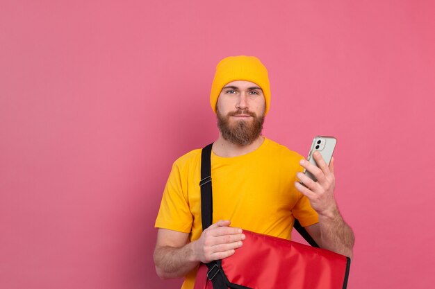 Entregador europeu alegre com bolsa casual segurar telefone rosa