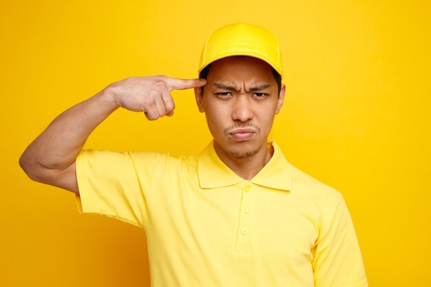 Entregador jovem confuso usando boné e uniforme fazendo gesto de pensar