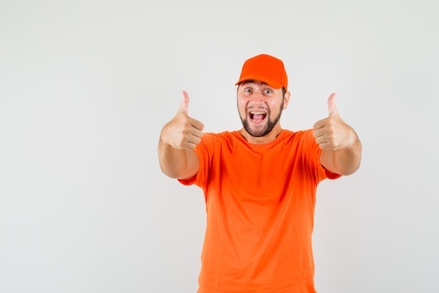 Entregador mostrando dois polegares para cima em camiseta laranja, boné e parecendo feliz. vista frontal.