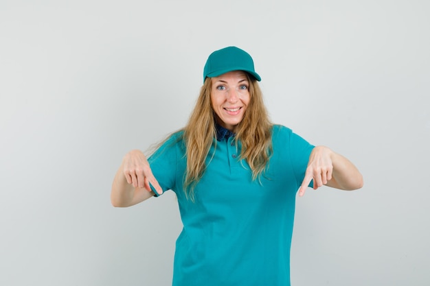 Entregadora com camiseta, boné apontando para baixo e parecendo alegre