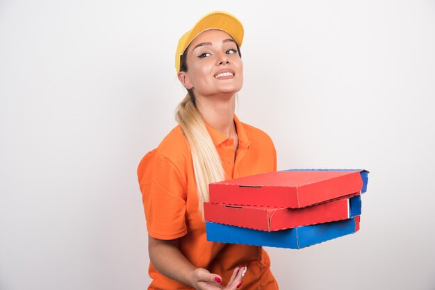 Entregadora com chapéu amarelo segurando caixas de pizza no espaço em branco