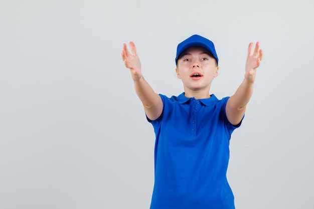 Foto grátis entregadora de camiseta azul e boné esticando os braços como se estivesse recebendo algo