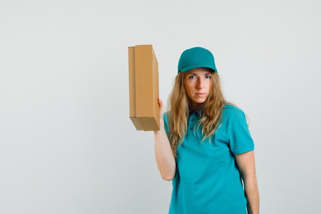 Entregadora de camiseta, boné segurando uma caixa de papelão