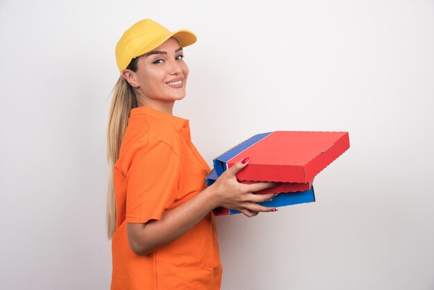 Entregadora de pizza segurando caixas de pizza com rosto tranquilo em um espaço em branco