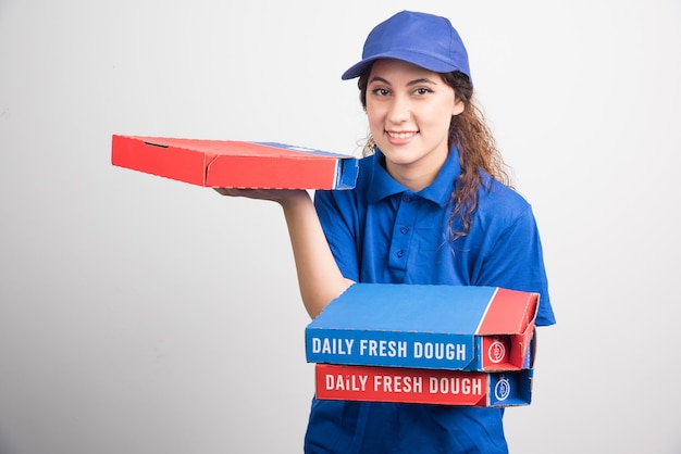 Entregadora de pizza segurando três caixas em fundo branco. foto de alta qualidade