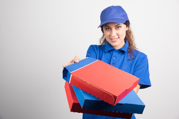 Entregadora de pizza segurando três caixas em fundo branco. Foto de alta qualidade