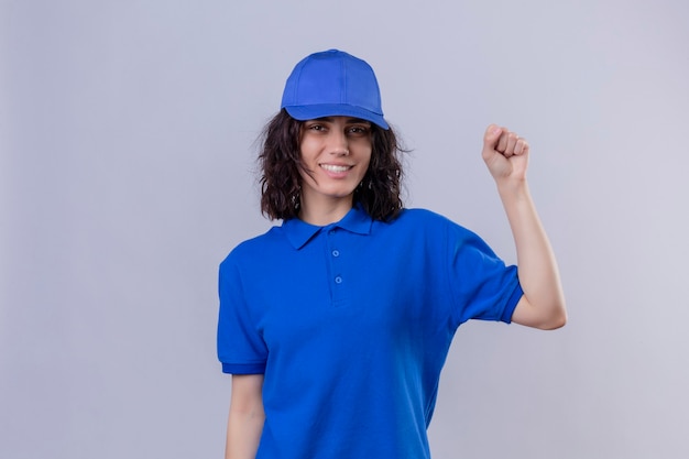 Entregadora de uniforme azul e boné levantando o punho após um conceito de vencedor da vitória sobre um espaço em branco isolado