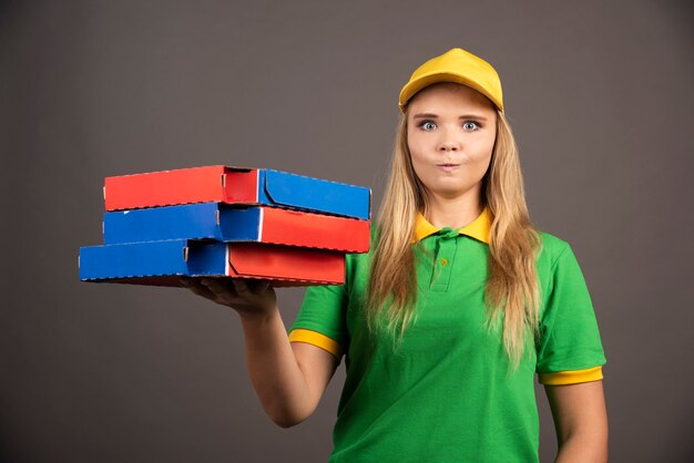 Foto grátis entregadora de uniforme segurando cartolinas de pizza.