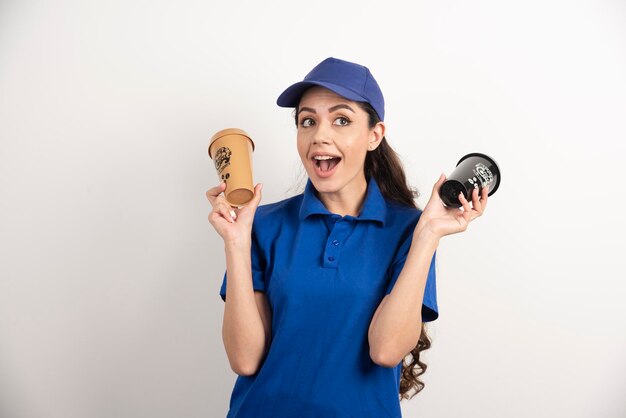 Entregadora feliz e positiva com xícaras de café. Foto de alta qualidade