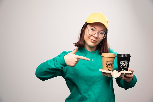 Entregadora mostrando papelão de xícaras de café em um branco. foto de alta qualidade