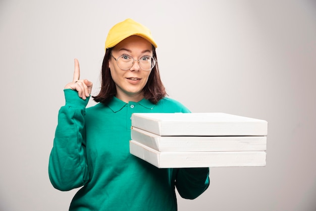 Entregadora mostrando um polegar para cima e segurando cartolinas de pizza em um branco. foto de alta qualidade