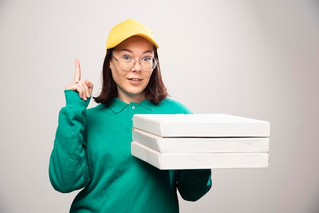 Entregadora mostrando um polegar para cima e segurando cartolinas de pizza em um branco. Foto de alta qualidade