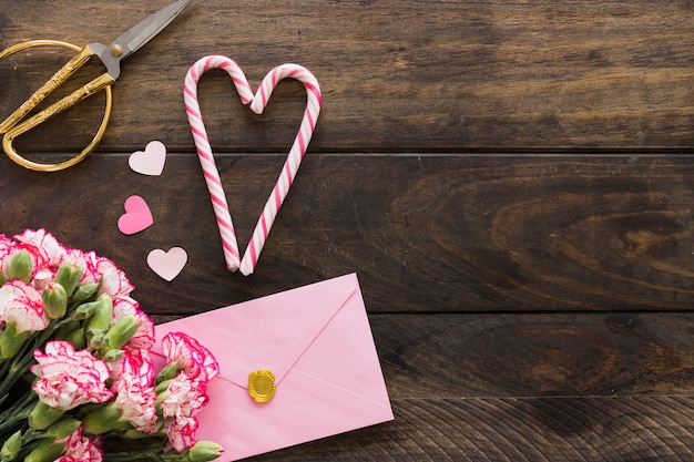 Foto grátis envelope perto de buquê de flores, tesouras e bastões de doces