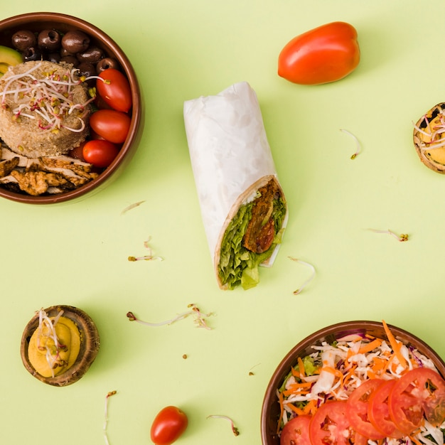 Envoltório de burrito com arroz; cogumelo recheado; salada e sobremesa em fundo verde