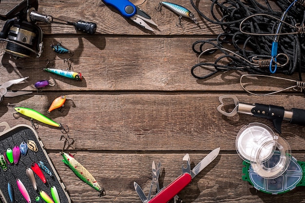 Equipamento de pesca de pesca, fiação, linha de pesca, anzóis e iscas em fundo de madeira