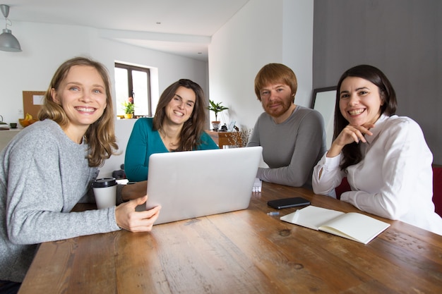 Equipe bem sucedida de quatro posando na sala de reuniões