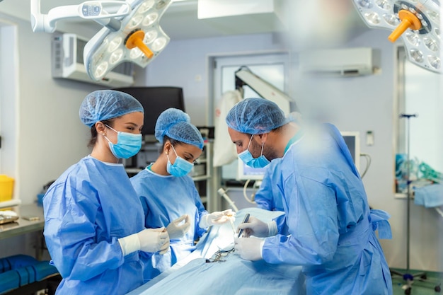 Equipe cirúrgica concentrada operando um paciente em uma sala de operações Anestesiologista bem treinado com anos de treinamento com máquinas complexas acompanha o paciente durante toda a cirurgia