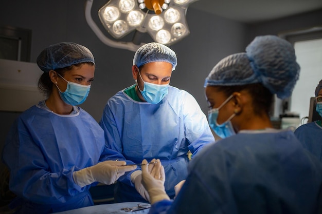 Equipe cirúrgica realizando cirurgia no moderno centro cirúrgicoequipe de médicos concentrando-se em um paciente durante uma cirurgiaequipe de médicos trabalhando juntos durante uma cirurgia na sala de cirurgia