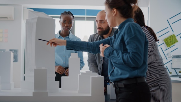 Equipe de arquitetos analisando modelo de construção para planejar layout de construção e plantas em papel. Pessoas arquitetônicas trabalhando com maquete para projetar estrutura e desenvolvimento de projetos.