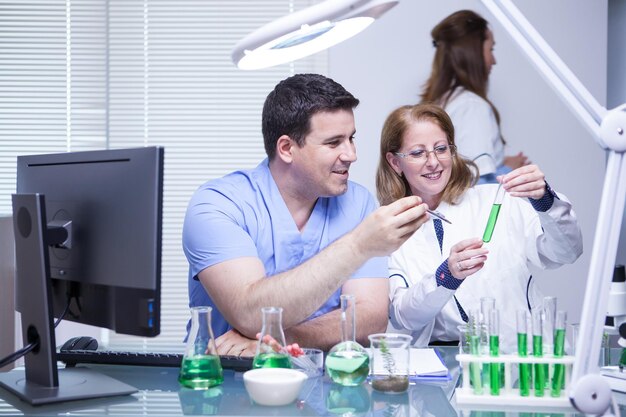 Equipe de cientistas avançados verificando a solução de um tubo de ensaio em seu laboratório. Laboratório de pesquisa