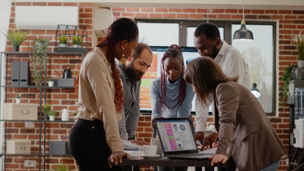 Equipe de colegas analisando gráficos em documentos para planejar o projeto, trabalhando juntos para projetar apresentação para crescimento e desenvolvimento de negócios. Grupo de colegas de trabalho fazendo trabalho em equipe no trabalho da empresa.