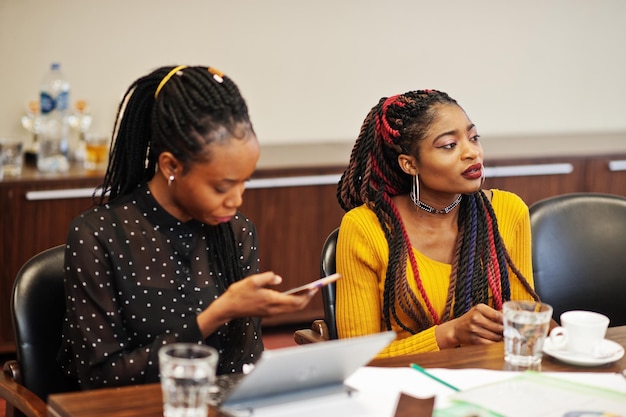 Equipe de colegas de mulheres afro-americanas de parceiras femininas de diversidade no escritório sentam-se à mesa