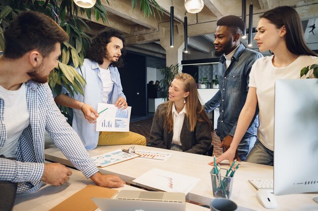 Equipe de diversos colegas de trabalho em um escritório moderno discute seu projeto juntos