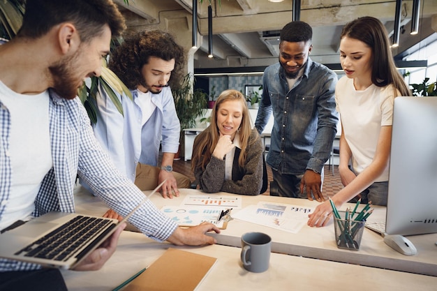 Equipe de diversos colegas de trabalho em um escritório moderno discute seu projeto juntos