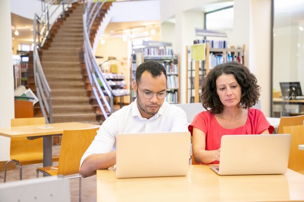 Equipe de dois estudantes adultos fazendo pesquisa