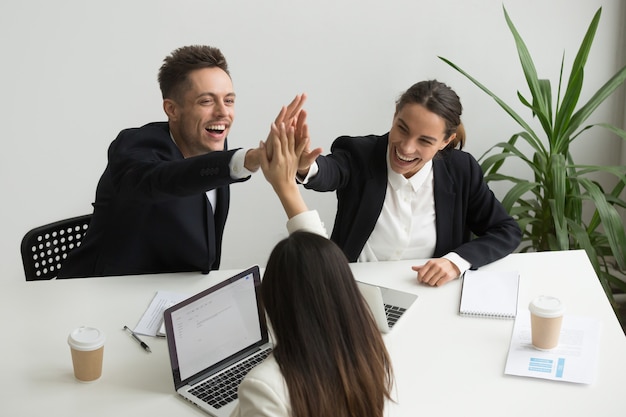 Foto grátis equipe de escritório milenar animado dando cinco juntos, conceito de teambuilding