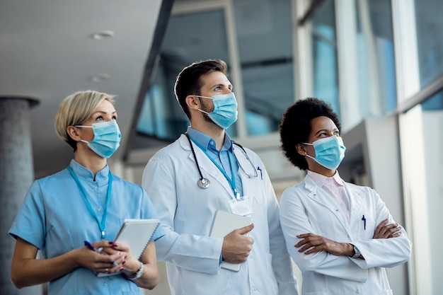 Equipe de especialistas médicos com máscaras faciais no hospital durante a pandemia de coronavírus