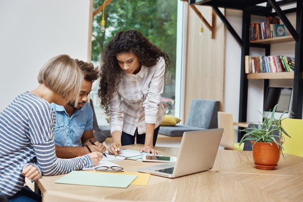 Equipe de jovens empreendedores criativos trabalhando no projeto de equipe, olhando através de informações sobre lucros no laptop, escrevendo idéias no papel. Brainstorm conceito.