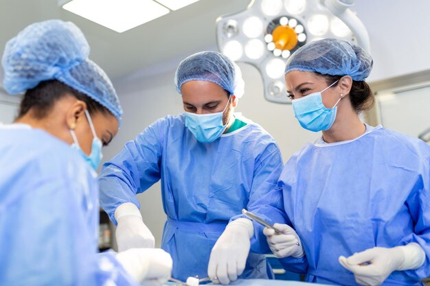 Equipe de médicos está de pé na sala de emergência Cirurgiões multiétnicos estão trabalhando na sala de cirurgia do hospital Eles estão vestindo uniforme azul