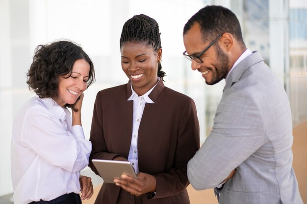 Equipe de negócios unida feliz assistindo vídeo no tablet