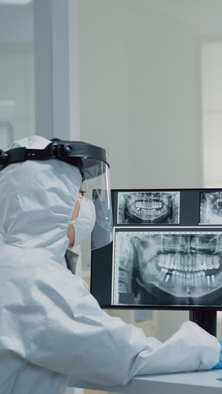 Foto grátis equipe de odontologia médica com ternos de ppe usando tecnologia moderna enquanto consulta o paciente com questões de higiene bucal. estomatologista e enfermeira dentária observando modelo de animação de dentes para implante