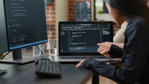 Equipe de programadores falando sobre algoritmo em execução na tela do laptop apontando para o código-fonte enquanto está sentado na mesa. desenvolvedores de software colaborando no projeto do grupo de codificação de dados.