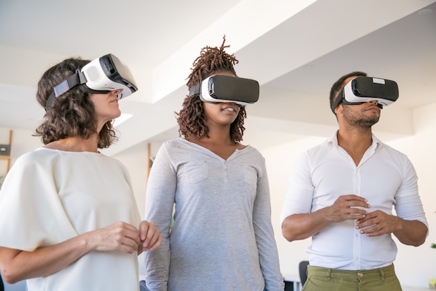 Equipe diversificada de três desfrutando de experiência em VR