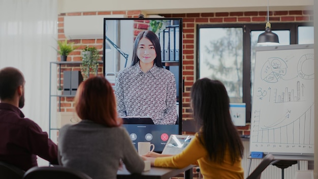 Equipe diversificada participando de reunião por videochamada online com colega, falando sobre colaboração de negócios para crescimento e desenvolvimento. pessoas usando videoconferência remota na sala de reuniões.