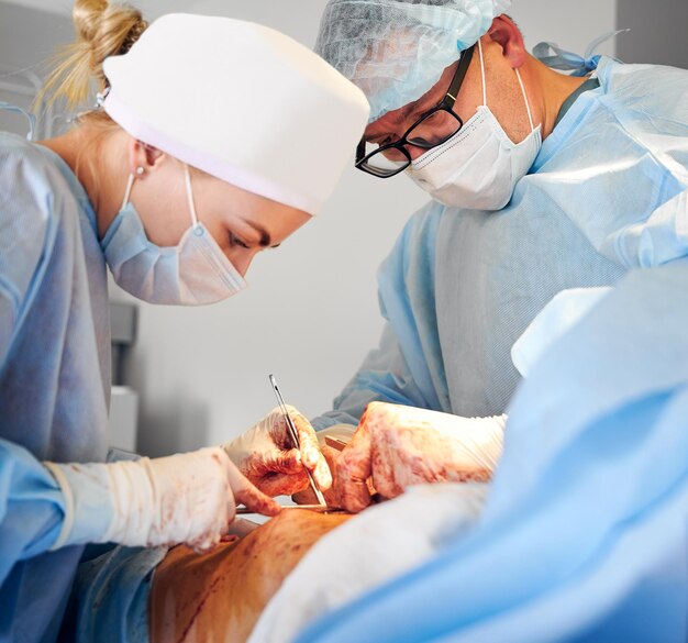 Equipe médica realizando cirurgia de abdominoplastia na sala de cirurgia