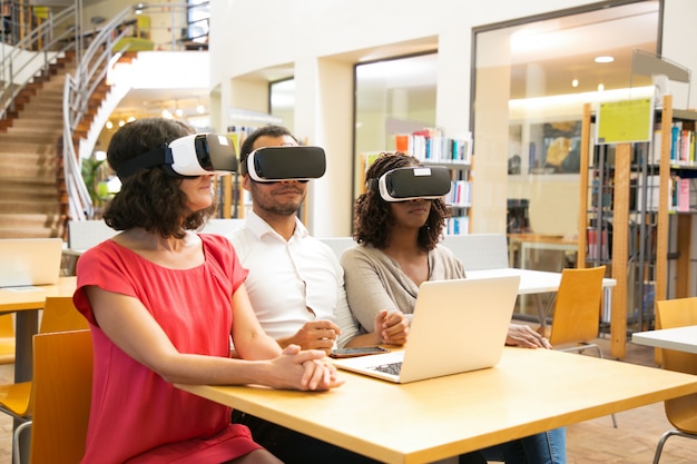 Equipe multirracial de estudantes adultos usando fone de ouvido VR