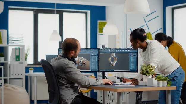 Equipe profissional da indústria pesada de engenheiros trabalhando em computador com dois monitores usando cad softwa ...