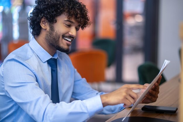 Escolhendo o almoço. Jovem empresário de cabelos escuros verificando o menu e escolhendo o almoço