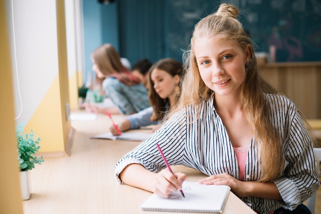 Foto grátis escrita encantadora de estudantes no bloco de notas