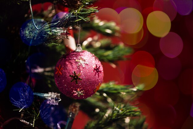 Esfera do Natal na árvore com bokeh no fundo vermelho