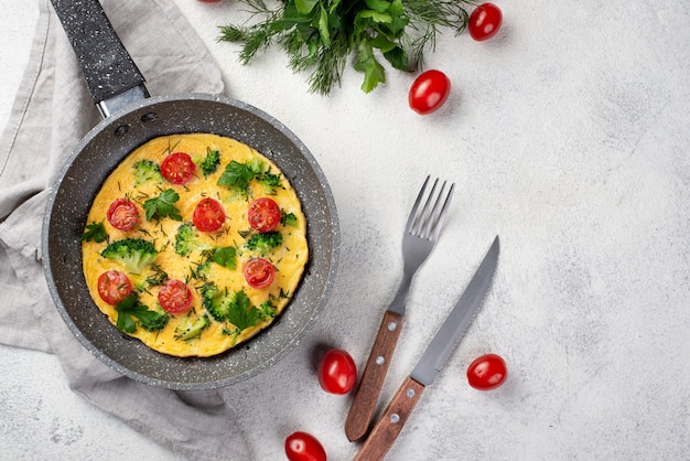 Esfolar colocar de omelete de café da manhã na panela com tomates e talheres