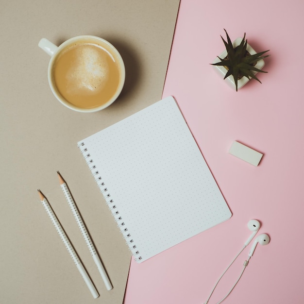 Espaço de trabalho mínimo de mesa em casa com caneca de café de caneta de prancheta em fundo rosa pastel e cinza Vista superior plana